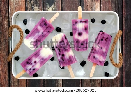 Group of blueberry vanilla ice pops in a vintage ice tray with rustic wood background