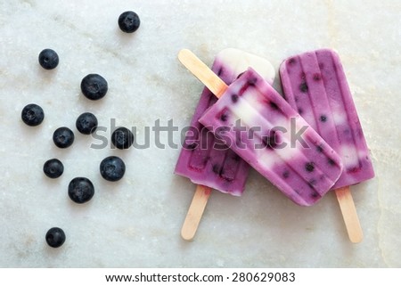 Blueberry vanilla ice pops in a cluster on a white marble background