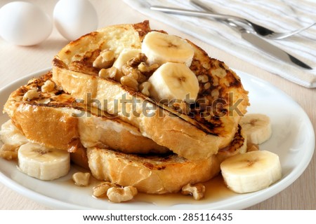 Plate of delicious French toast with bananas, walnuts and dripping maple syrup