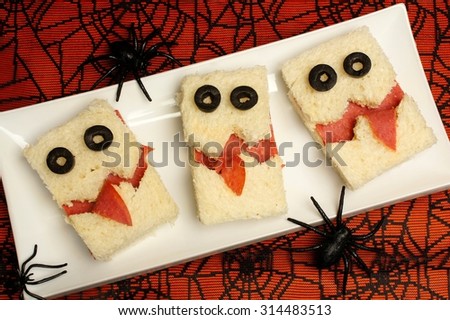 Fun Halloween monster sandwiches on a plate with spiderweb background