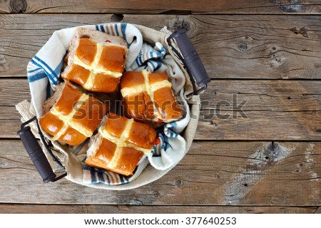 Easter Hot Cross Buns in a basket, downward view on a rustic wood background