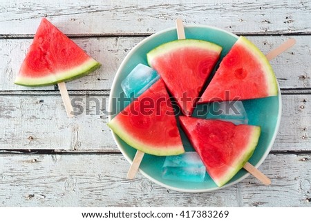 Watermelon slice popsicles on a vintage blue plate and rustic wood background