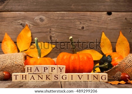 Happy Thanksgiving wooden blocks against a rustic wood background with pumpkins and autumn leaves