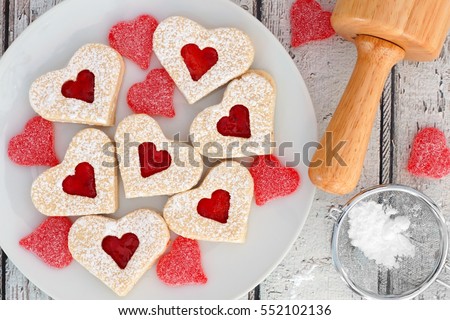 Heart shaped Valentines Day cookies with jam and candies, overhead scene on white wood
