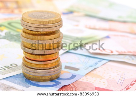 Single stack of coins with bank notes in the background