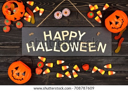 Happy Halloween black sign with wood letters and frame of candy on a black wood background