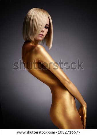 Fashion art studio photo of elegant nude woman with golden body. Fashion and beauty. Conceptual image. Metallic art, body art. Slim, fit woman. Gold skin