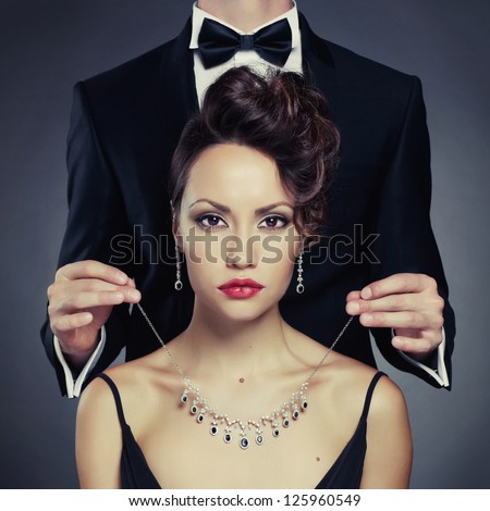 Elegant man on a beautiful woman wears a necklace
