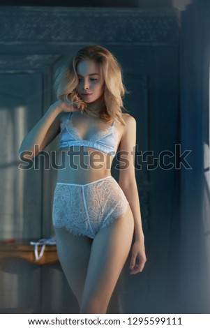 Fashion art photo of beautiful sensual woman in sexy lingerie. Home interior. Beautiful morning light in the dark room. Pretty lady with perfect body pose in hotel.