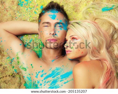 Romantic couple painted colored powders on the sand. Holi festival, India