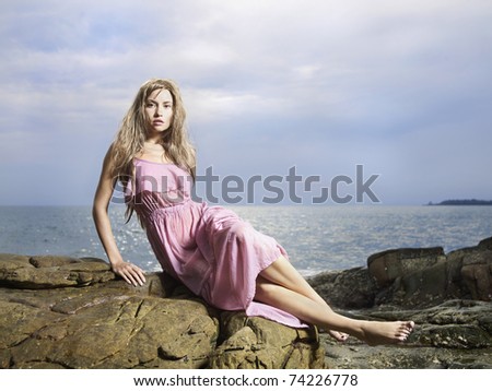 stock photo Photo of beautiful woman in wet clothes on a rocky seashore