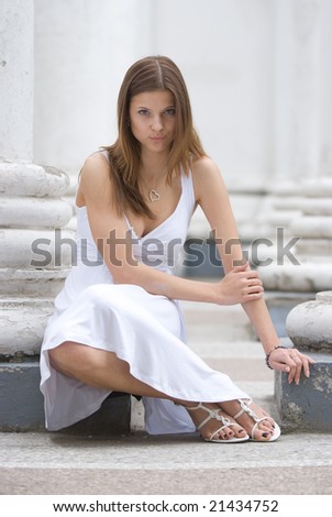 GIrl in a white dress sitting among columns