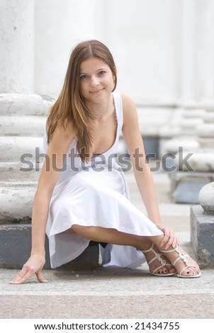 Girl in a white dress sitting among columns