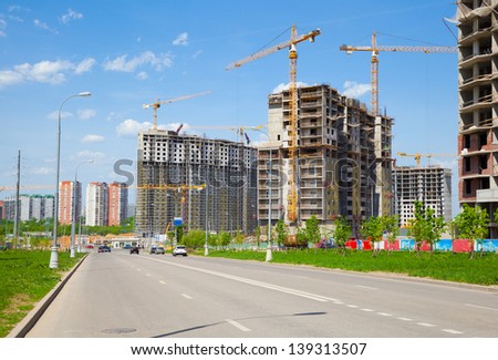 Building under construction, yellow construction crane, street.