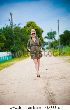 pretty girl walking on a rural road in green dress
