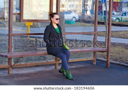 Girl sitting on a bench waiting for transport at the bus stop