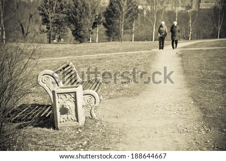 People stroll in the park bench in the foreground. black and white photo