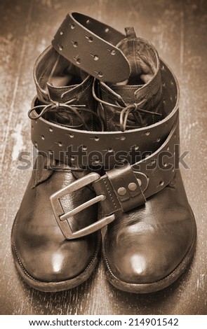 Fashionable leather boots and brown leather belt with gold buckle. Vintage style. Handmade. Autumn and spring shoes. Photo toning in sepia