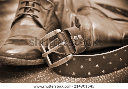 Fashionable leather boots and brown leather belt with gold buckle. Vintage style. Handmade. Autumn and spring shoes. Photo toning in sepia