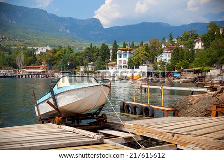 The Crimean landscape in summer. View of the waterfront, the city beach. Boat on the docks in the foreground.