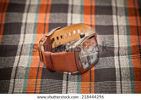 wristwatch with a leather strap on a plaid background