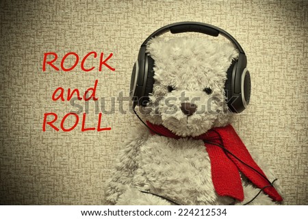 Toy teddy bear with a red scarf listening to music on headphones. A fan of rock music, retro style. Photo tinted in yellow