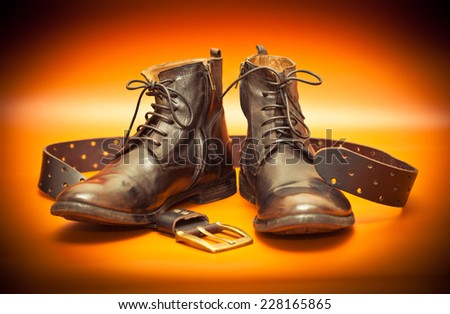 Men\'s leather shoes and a leather belt with a buckle.Photo toned in yellow