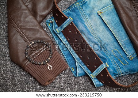 Fashion trend: jeans, leather jacket, leather belt, bracelet on the arm. Youth Clothing