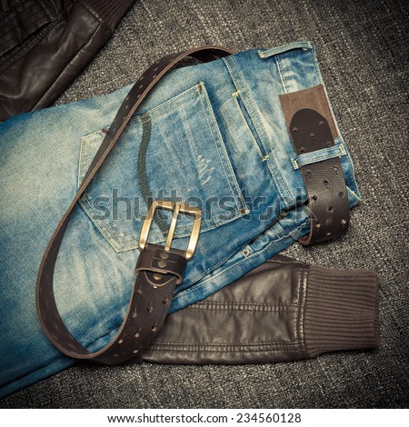 Fashion trend: blue frayed jeans, a leather jacket and leather belt with buckle