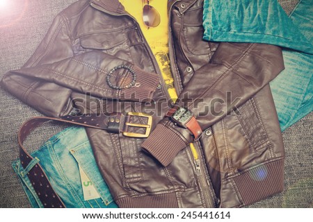 urban fashion clothing: leather jacket, jeans, belt, watch, bracelet, sunglasses. Photo in vintage style
