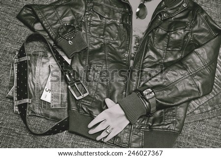 Fashion and accessories: leather jacket, jeans with a belt, shirt, watches, bracelets, gloves, sunglasses, note 5 Euro. Retro style, black-and-white photo