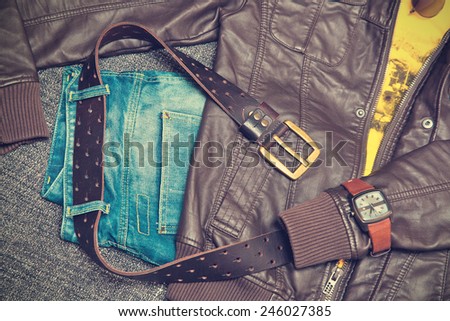 Fashion concept. Clothing items: leather twist, jeans, T-shirt, belt, watch and bracelet. Vintage style