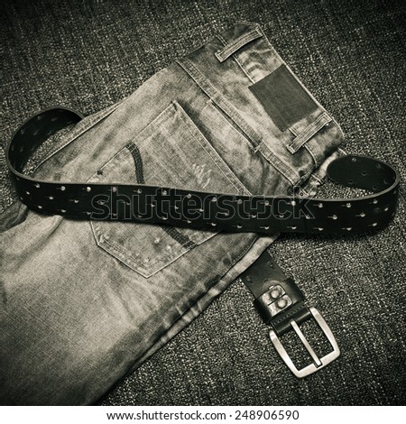 Details of clothes: fashion jeans, a leather belt with a buckle. Black and white photo in retro style