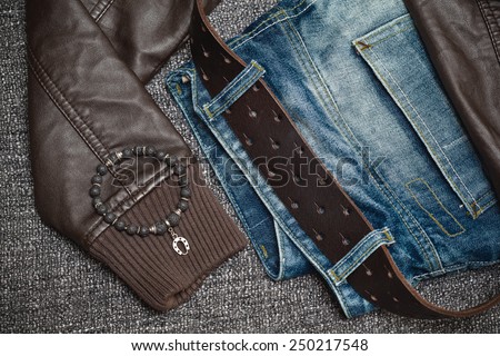 youth clothes: jeans with a leather belt, leather jacket, jewelry bracelet on the arm