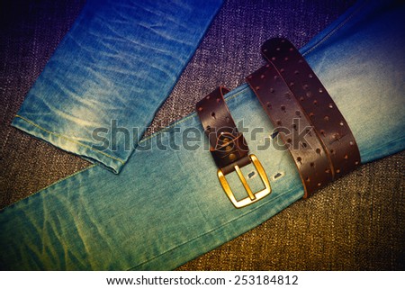 Blue jeans and a leather belt with a gold buckle. Youth trend. Photo toned in yellow and purple.