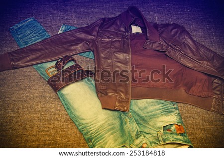 Fashionable youth clothes: jeans, leather jacket, leather belt. Photo toned in yellow and purple.