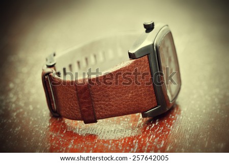 Watch with a leather strap on a wooden table