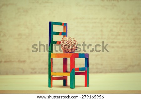 Toy wooden chair and woven decorative ball. Contemporary art