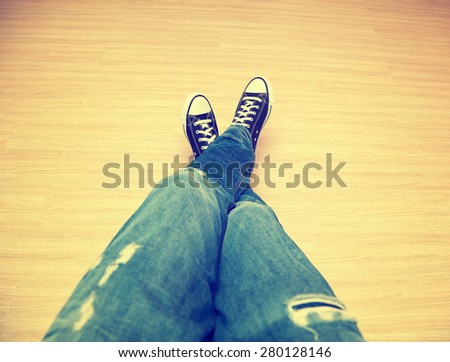 Foot teenager in jeans and classic sneakers - a top perspective view. Photo toned in yellow style instagram