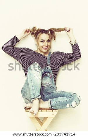 Funny girl with pigtails smiling sitting on a stool