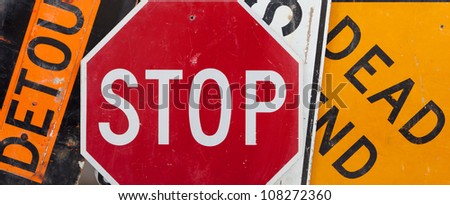 Old, vintage traffic signs including a stop sign, a detour sign, and a dead end sign making a background.  Caution theme