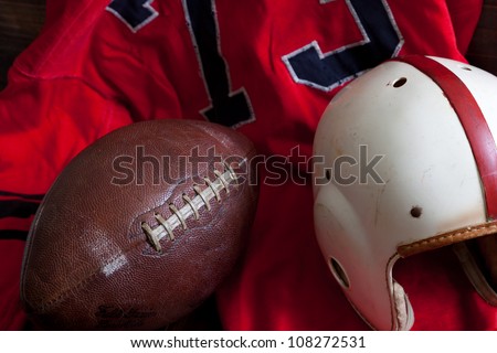 A group of vintage, antique American football equipment including a jersey, football and a helmet
