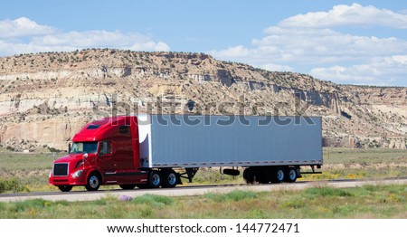 A semi-truck on the road in the desert
