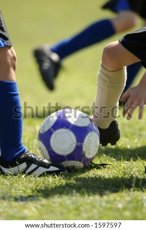 Several set of feet trying to control soccer ball - football