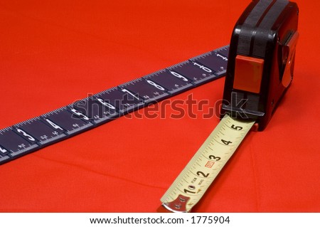 Measuring tape and ruler on red background