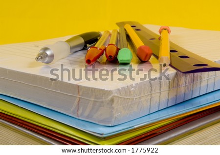 school supplies on yellow background with pen, pencils, rulers, paper and folders