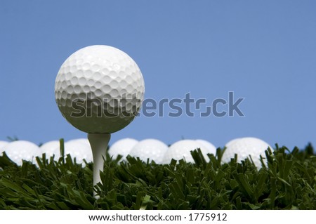 golf ball on tee on grass with blue sky