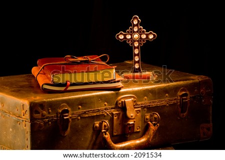 Vintage, antique religious items painted with light.  Missionary items including a Bible, journal, suitcase and cross. focus is on cross with a glint of light on one of the crystals on cross