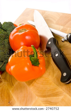 Assorted fresh vegetables on cutting board with chefs - cooks knife