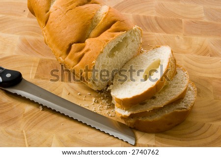 slicing bread on wood cutting board with a bread knife